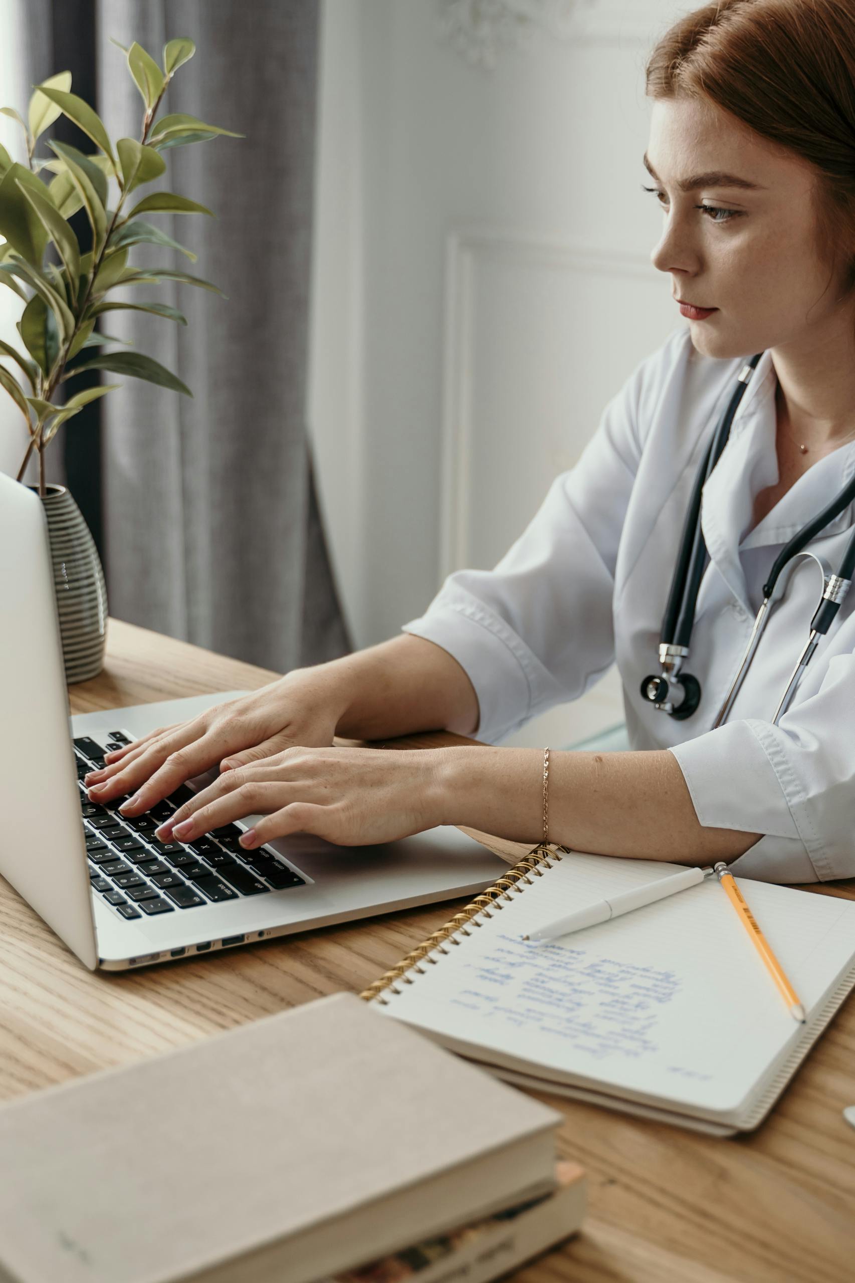 A Woman in White Long Sleeves Typing on Her Laptop